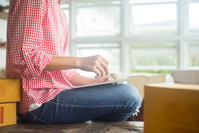 Midsection of young woman using digital tablet at home