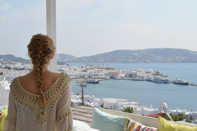 Woman looking at sea by mountains against sky