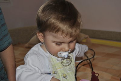 Close-up of cute boy with pacifier in mouth by father on bed at home