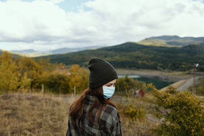 Man wearing hat standing on land against sky