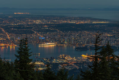 Aerial view of harbor amidst illuminated cityscape at night