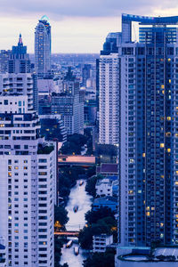 Modern buildings in city against sky at dusk