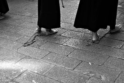 Low section of people wearing metallic chains walking on footpath