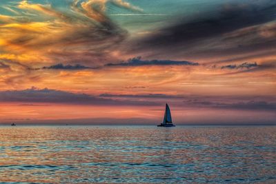 Sailboat sailing on sea against sky during sunset