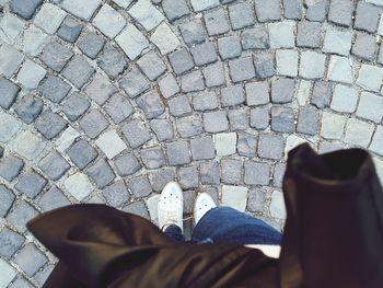 Low section of man standing on cobblestone street