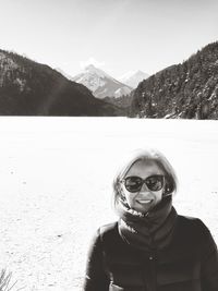 Portrait of young woman in sunglasses against mountains