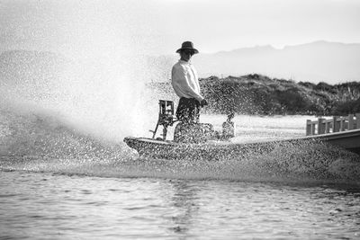 Man riding motorcycle on lake against sky