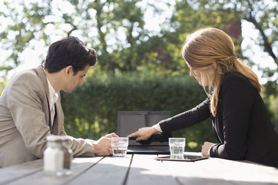 Businesswoman discussing with male colleague through laptop at outdoor cafe