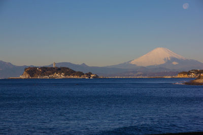 Scenic view of sea and mountains against clear blue sky