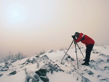 Photographer takes picture of freeze autumnal daybreak, rocks covered with fresh powder snow. 