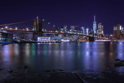 Illuminated bridge over river at night