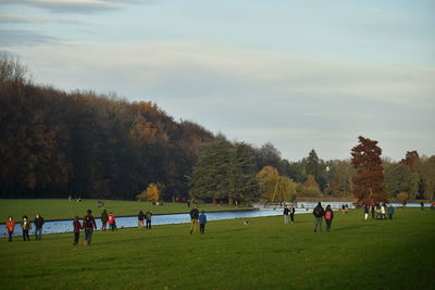 Group of people playing soccer on field against sky