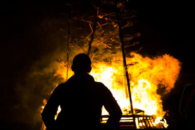 Silhouette person against fire at night