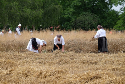 People standing on field against trees