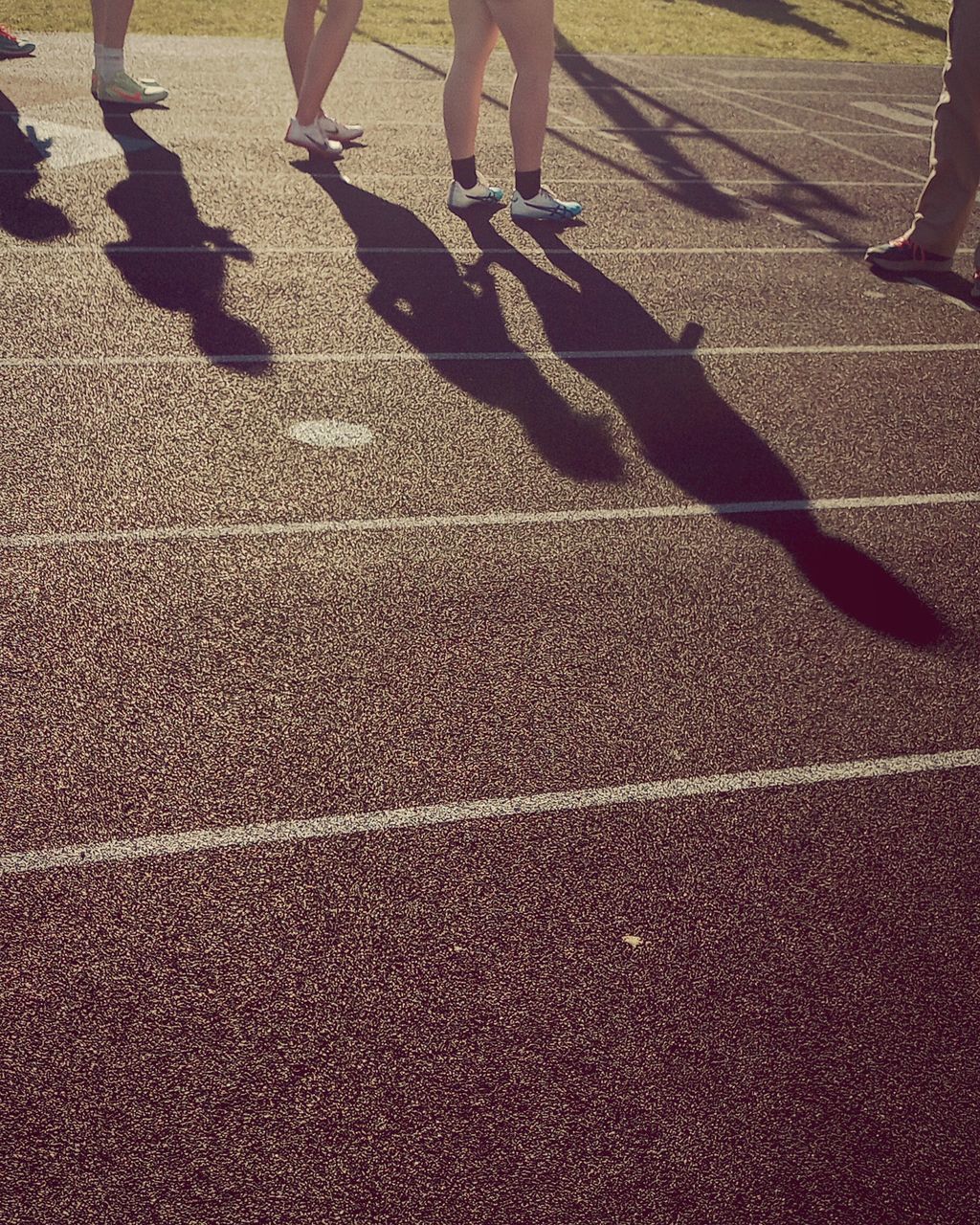 low section, human leg, shadow, flooring, group of people, sunlight, lifestyles, men, day, asphalt, human limb, sports, road surface, limb, shoe, women, adult, leisure activity, nature, floor, walking, outdoors, togetherness, footwear, road, person, high angle view, lane, competition, standing, black, running track