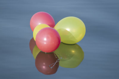 Close-up of multi colored balloons on water against blue background