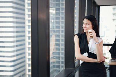 Full length of a beautiful young woman standing by window