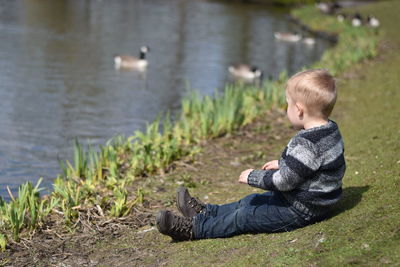 Full length of boy sitting on grassy field