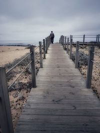 Boardwalk leading towards sea against sky