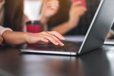 Cropped hand of woman using laptop