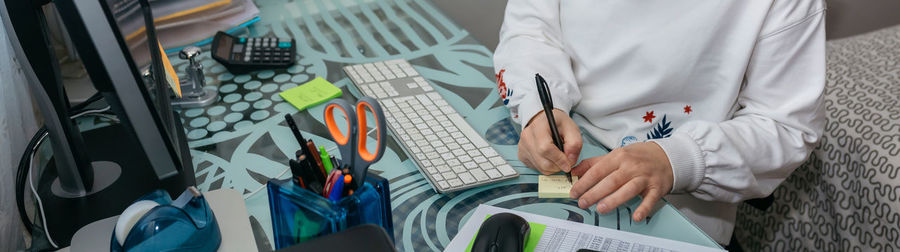 Midsection of woman writing on adhesive note