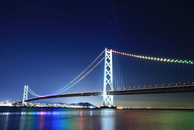 Illuminated akashi kaikyo bridge over sea against clear sky at night