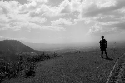 Rear view of man walking on mountain against sky