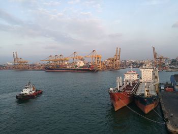 Boats moored at harbor against sky in city