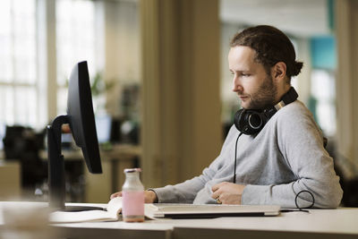 Young man using mobile phone while sitting on table