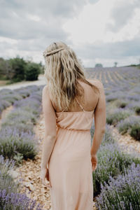 Rear view of woman standing on field against sky