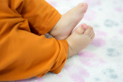 Low section of baby lying on bed