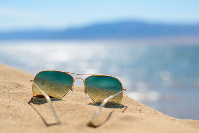 Close-up of sunglasses on sand at beach