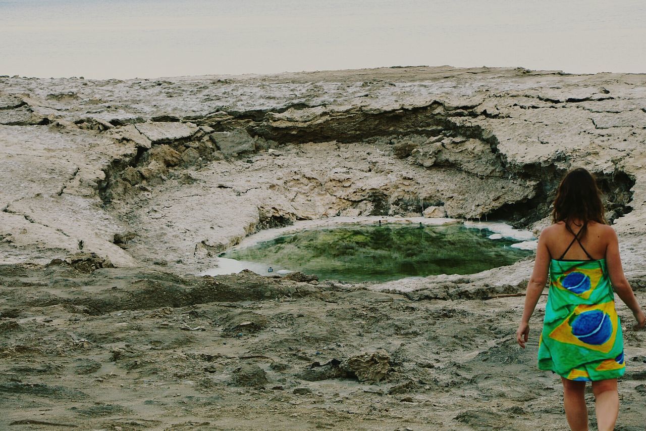 lifestyles, leisure activity, beach, sea, men, water, standing, sand, holding, person, vacations, shore, rear view, rock - object, day, nature, outdoors, casual clothing