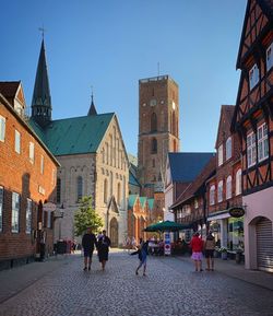 People outside buildings in city against clear sky