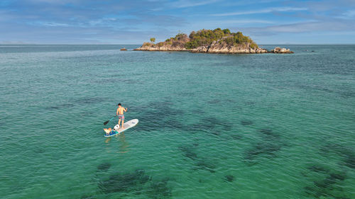 High angle view of man paddleboarding with dog in sea