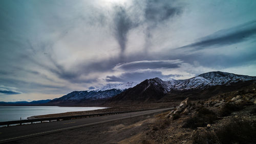 Scenic view of road by mountains against sky