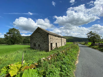 Looking down, dubb's lane, with fields, a barn, and hills in the distance near, buckden, skipton, uk
