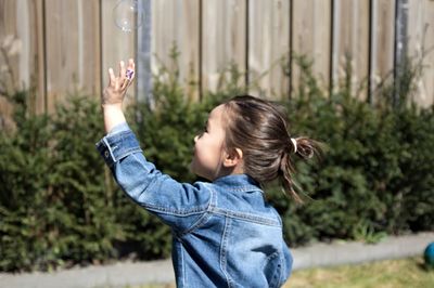 Side view of a girl standing against plants