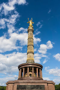 Low angle view of victory column against cloudy sky during sunny day