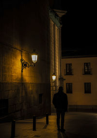 Rear view of adult man walking on street with light of street lamp at night. shot in madrid, spain