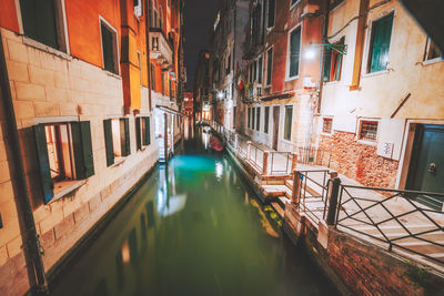 Canal amidst buildings in city at night