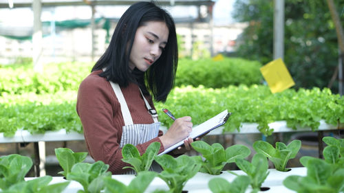 Young woman looking away while plants