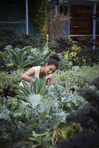 Young woman analyzing plants at yard