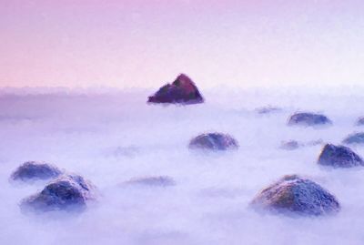 Scenic view of rocks in sea against sky during winter