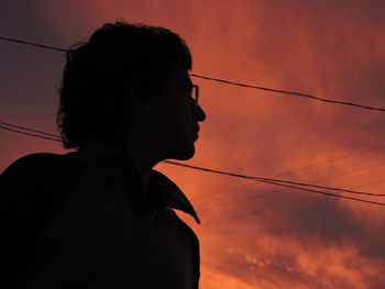 Low angle view of silhouette thoughtful man standing against cloudy sky during sunset