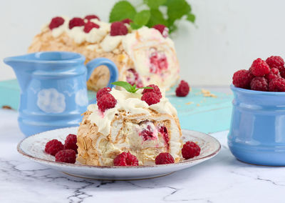 Baked meringue roll with cream and fresh red raspberry, white background