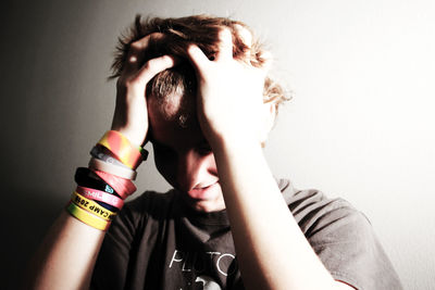 Young man with hands in hair against wall