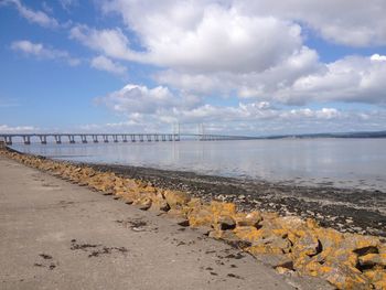 Pier on sea against cloudy sky