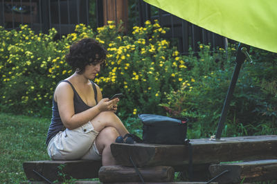 Side view of young woman sitting in yard