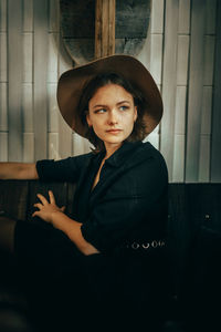 Portrait of young woman standing against wall